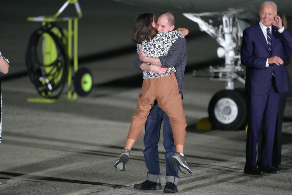 Reporter Evan Gershkovich hugs his mother, Ella Milman, as President Joe Biden, right, looks on at Andrews Air Force Base, Md., following their release as part of a 24-person prisoner swap between Russia and the United States, Thursday, Aug. 1, 2024. (AP Photo/Manuel Balce Ceneta)