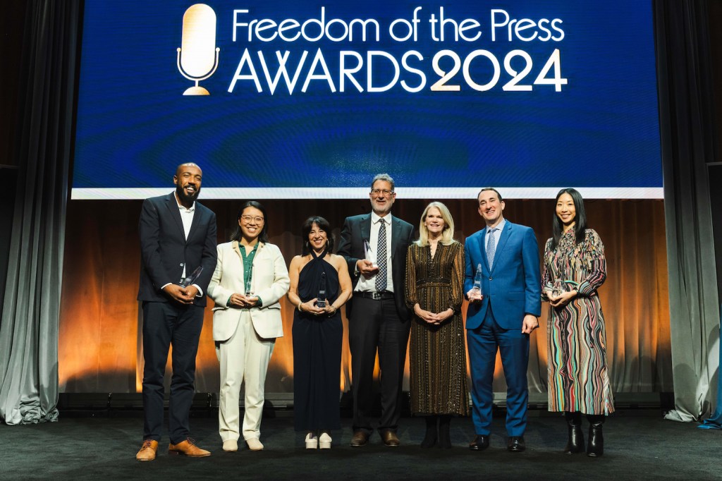 Freedom of the Press Award honorees standing on a stage. From left: Mazin Sidahmed, Sisi Wei, Maria Hinojosa, Stephen Engelberg, host Martha Raddatz, Jason Criss, and Josie Huang.